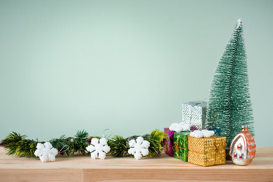 Christmas background. A small Christmas tree and boxes with gifts on a wooden table. Green background. Space for text. New Year's background.