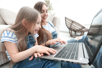 Naklejka premium happy mother with adorable little girl with laptop