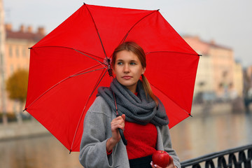 Girl on a walk with a red umbrella and an Apple