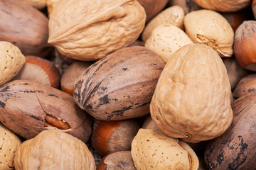 Macro shot of different nuts: almond, walnut, hazelnut and pecan on burlap background.