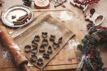 Christmas gingerbread cookies dough with metal cutters on rustic table with wooden rolling pin, cinnamon ,anise, cones, christmas decorations. Atmospheric stylish image, winter holidays
