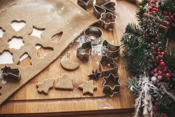 Making christmas gingerbread cookies. Tree and stars dough, metal cutters on rustic table with  cinnamon ,anise, cones, christmas decorations. Atmospheric stylish image