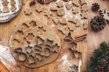 Making christmas gingerbread cookies flat lay. Dough with metal cutters on rustic table with wooden rolling pin, cinnamon ,anise, cones, christmas decorations. Atmospheric stylish image