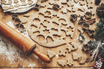 Making christmas gingerbread cookies. Dough with metal cutters on rustic table with wooden rolling pin, cinnamon ,anise, cones, christmas decorations. Atmospheric stylish image