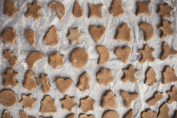 Making christmas gingerbread cookies flat lay. Raw cookies on baking tray. Trees, stars, jingle bells, gingerbread man, moons cookies top view. Atmospheric image