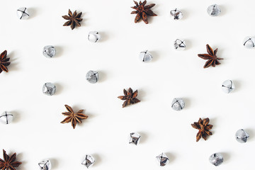 Christmas styled stock composition. Glittering silver jingle bells and anise stars on white background. Flat lay, top view. Winter decorative pattern.