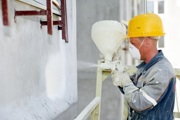 Facade work. Worker painting by spreading white paint