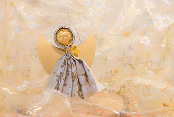 Selbstgebastelter Engel aus einer Serviette, Stoff Hintergrund mit goldenen und silbernen Sternen