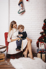 Mother and sun sitting on a chair and firing sparklers in Christmas decorated studio