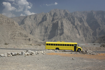 american yellow school bus in desert mountains in united arab emirates