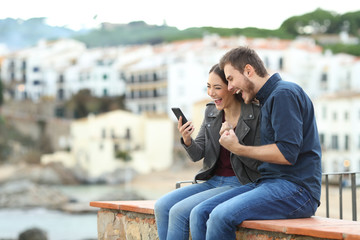 Excited couple finding news on phone on a ledge