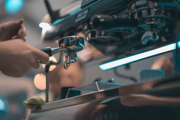 Close-up professional grinding freshly roasted coffee in espresso machine. Barista preparing coffee in bar. Concept of coffee making, service and catering