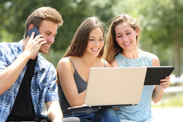 Three friends using multiple devices in a park