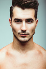 Male beauty concept. Portrait of handsome young man with stylish haircut. Perfect hair & skin. Close up. Studio shot
