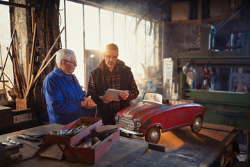 Obraz na płótnie Canvas A senior man and his son at workshop to restore an old pedal car