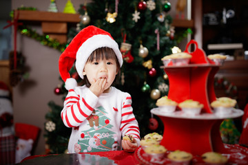 toddler baby girl eating mice pie in front of christmas tree