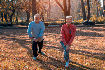 Man and woman exercise together outside in park