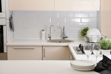 Stack of clean dishes and glasses on table in kitchen. Space for text