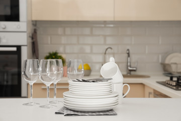 Clean dishes, glasses, cups and cutlery on table in kitchen