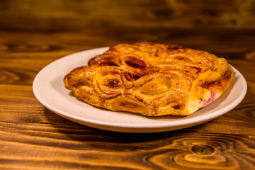 Ceramic plate with fresh cherry strudel on wooden table
