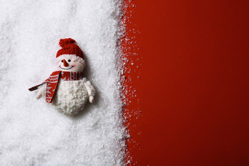 Composition with small decorative snowman on color background, top view