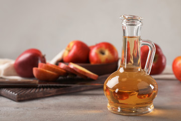 Composition with jug of apple vinegar on table. Space for text