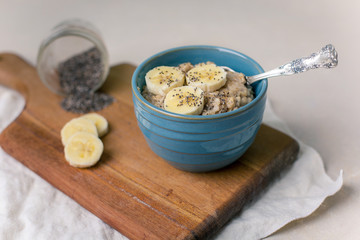 Oatmeal Porridge in a Blue Bowl with Sliced Bananas and Chia Seeds