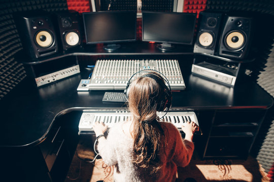 young woman is working in the music studio. close up back view shot. girl in headphone learning to play in the synthesizer.instrument