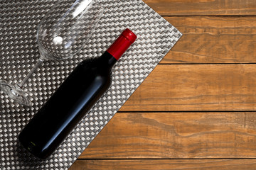 Bottle of wine and glass on wooden background. Top view with copy space.