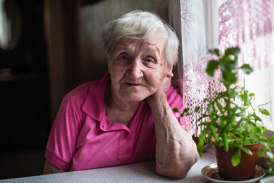Elderly woman sitting at the table in home.