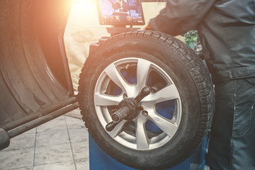 Mechanic worker makes computer wheel balancing on special equipment machine tool in auto repair service