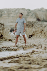 Young man on the beach, man walking on the rocky beach coastline