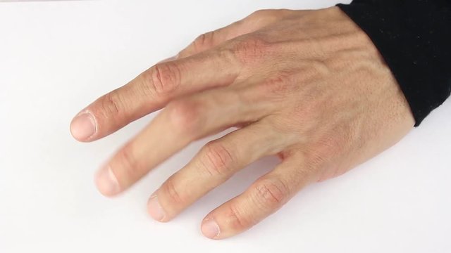 human hand nervously scratching and tapping fingers on white table