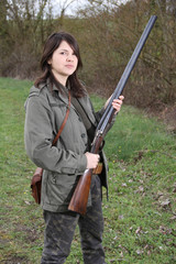 Fototapeta premium Proud woman hunter holding her vintage shotgun in the field