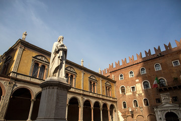 Fototapeta na wymiar Statue of Dante Alighieri in Piazza dei Signori, Verona, Italy. Beautiful statues of Dante in the middle of Verona old town with other sculptures and architecture. Summer day in Verona