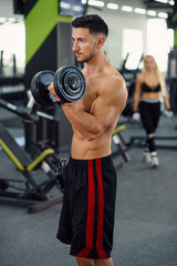 Fototapeta na wymiar Close up of sporty fitness man doing exercises for biceps using dumbbells on the stylish gym background.