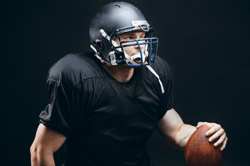 People, achievement and sport concept. Athletic american football player in black helmet and jersey...
