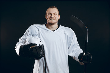 Naklejka premium Portrait of cheerful proud caucasian hockey player smiling with teeth, looking in camera with happy and relaxed face expression, posing after victory in hockey match with stick, isolated on white