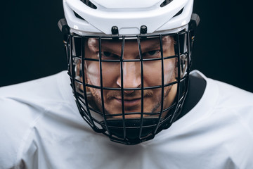 Head portrait of grinning hockey goalie with broken tooth wearing white helmet over black background