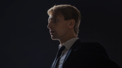 Profile of a brooding young man in a business suit. Portrait of a businessman