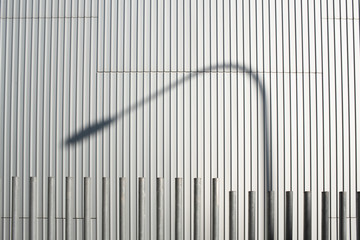 Background of vertical metallic lines with shadow of lamppost.