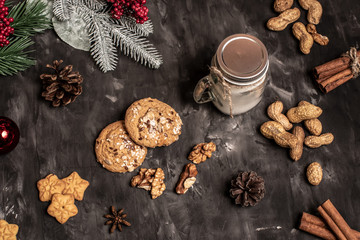 Christmas and new year table decoration background with garland, cookies, pine cones, wallnuts and candle in cup