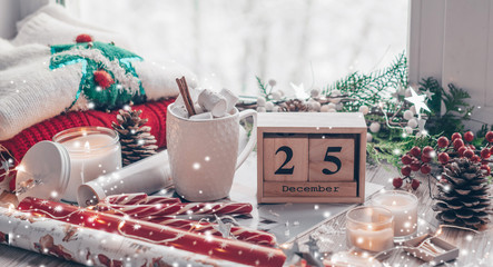 25 December Calendar. Christmas decor: Warm sweater, cup of hot cocoa with marshmallow, candy, candles and Christmas tree. Winter mood, holiday decoration.