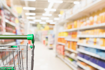 Empty green supermarket shopping cart with abstract blur grocery store aisle defocused background