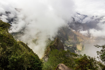 Fototapeta na wymiar Views over the mountains and rainforest around Machu Picchu Citadel an amazing an idyllic scenery to view during a foggy morning. An amazing green landscape to enjoy with our eyes. Inca Trail, Peru