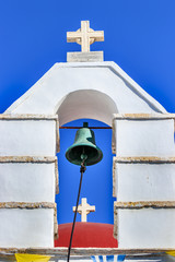 Two crosses in perspective with bell tower and a re dome in Mykonos, Greece.
