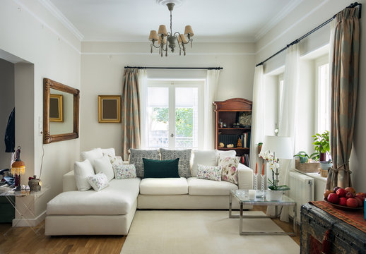 Large living room very bight  with oak wooden floor, four seats sofa, white carpet and retro objets, Greece.