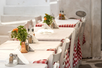 Perspective view of tables in a line outdoors in a Greek taverna in Mykonos, Greece.