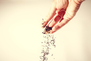 Black tea leaves tickling from the fingers off a white background
