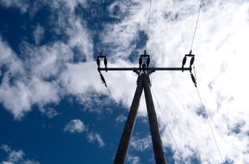 Fototapeta na wymiar Energy Industry: An overhead medium voltage power line with wooden poles in Eastern Thuringia in front of the cloudy blue April sky